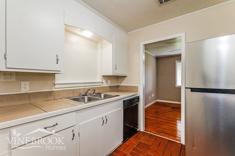 A kitchen with white cabinets and a refrigerator.