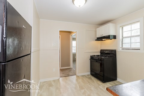 A kitchen with a black fridge and a black stove top oven.
