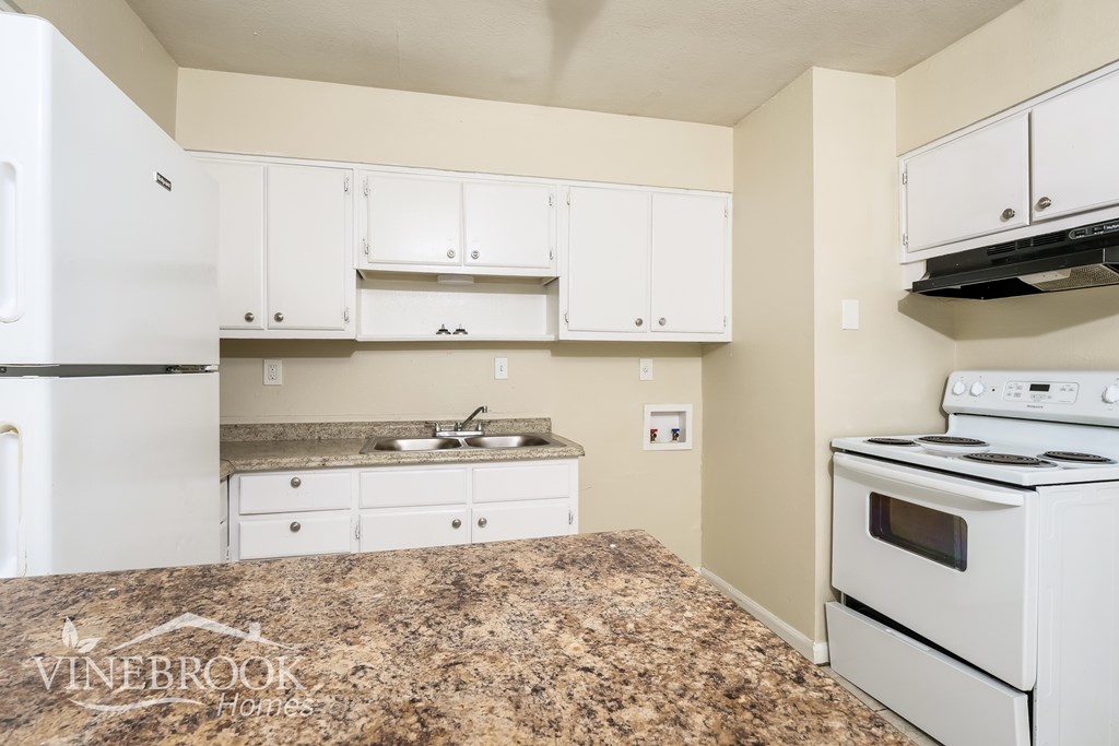 A kitchen with white appliances and cabinets.