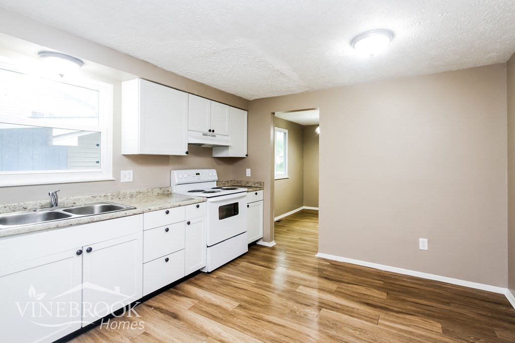 A kitchen with white cabinets and wooden floors.