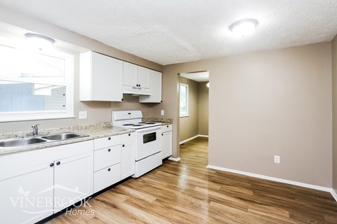 A kitchen with white cabinets and wooden floors.