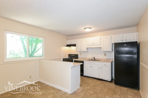 A kitchen with white cabinets and a black fridge.