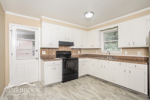 A kitchen with white cabinets and a black stove top oven.