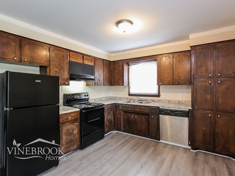 A kitchen with wooden cabinets and a black fridge.