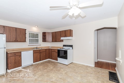A kitchen with wooden cabinets and a white ceiling fan.