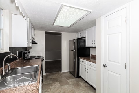 A kitchen with white cabinets and a black refrigerator.