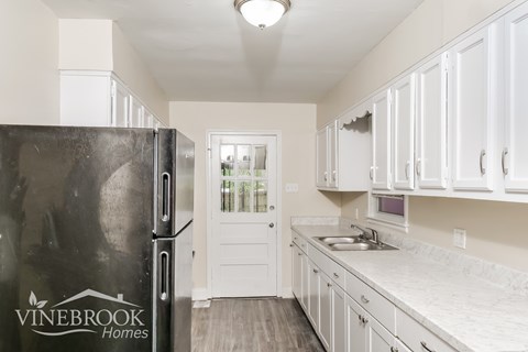 A kitchen with white cabinets and a black fridge.
