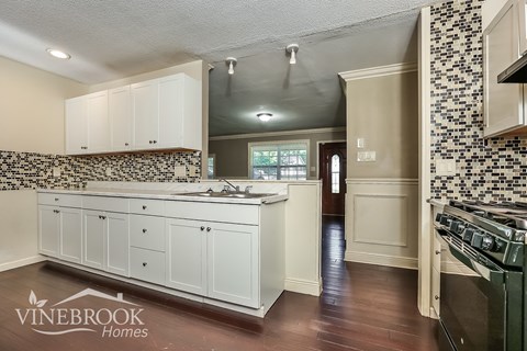 A kitchen with white cabinets and a black and white tiled backsplash.