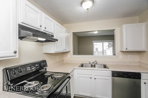 A kitchen with a black stove top oven and white cabinets.