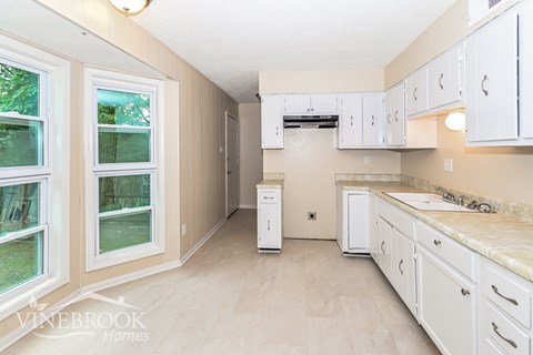A kitchen with white cabinets and a marble countertop.