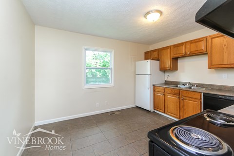 A kitchen with a stove top oven and wooden cabinets.