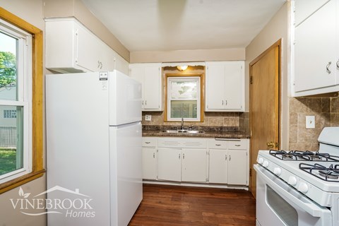 A kitchen with white appliances and wooden floors.