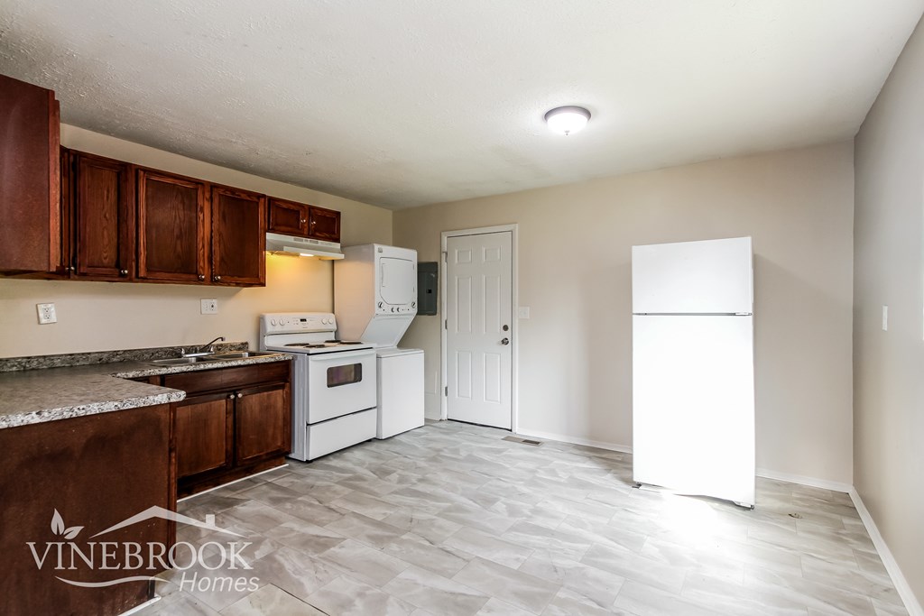 A kitchen with a refrigerator, oven, and cabinets.