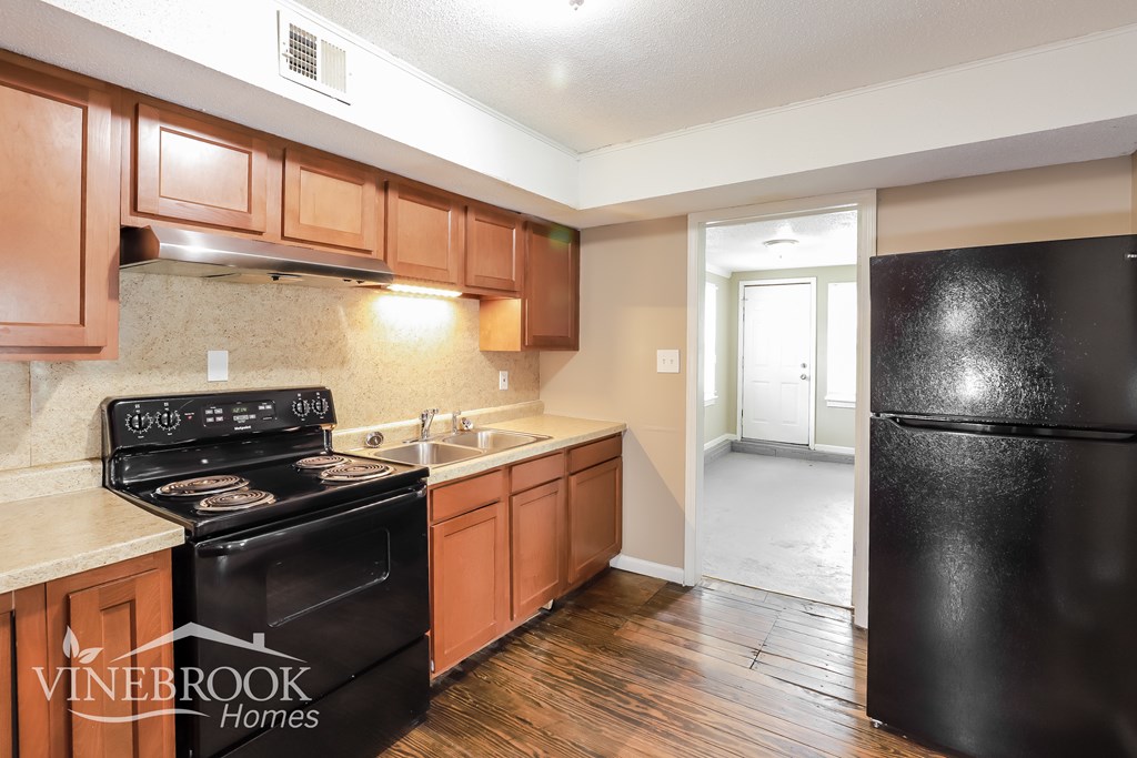 A kitchen with wooden cabinets and a black fridge.