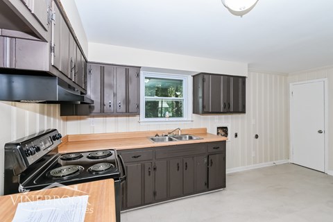 A kitchen with a black stove top oven and wooden countertops.