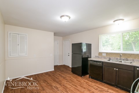 A kitchen with a refrigerator, cabinets, and a sink.