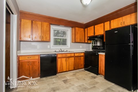 A kitchen with wooden cabinets and black appliances.