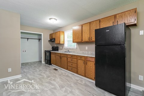 A kitchen with a black fridge and wooden cabinets.