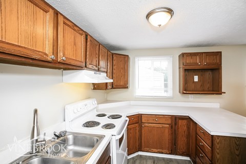 A kitchen with wooden cabinets and a white stove top oven.