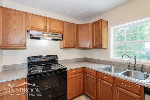 A kitchen with wooden cabinets and a black stove top oven.