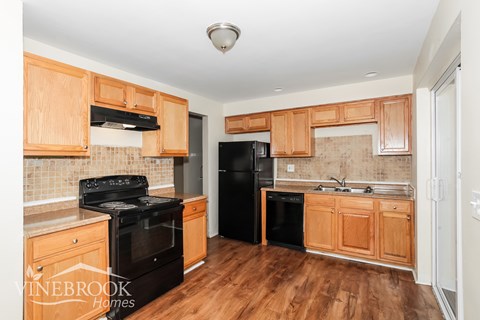 A kitchen with wooden cabinets and black appliances.