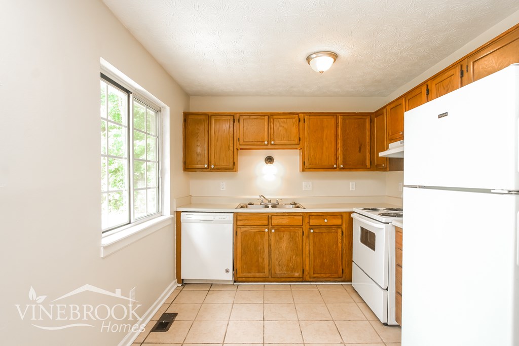A kitchen with wooden cabinets and white appliances.
