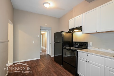 A kitchen with black appliances and white cabinets.