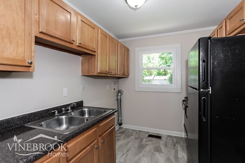 A kitchen with wooden cabinets and a black refrigerator.