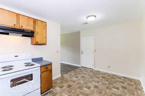 A kitchen with a stove top oven and a tiled floor.