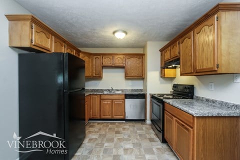 A kitchen with wooden cabinets and a black refrigerator.