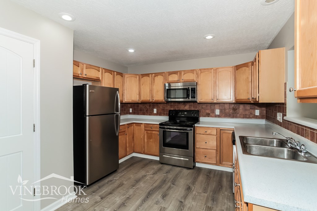 A kitchen with wooden cabinets and a stainless steel refrigerator.