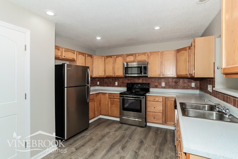 A kitchen with wooden cabinets and a stainless steel refrigerator.