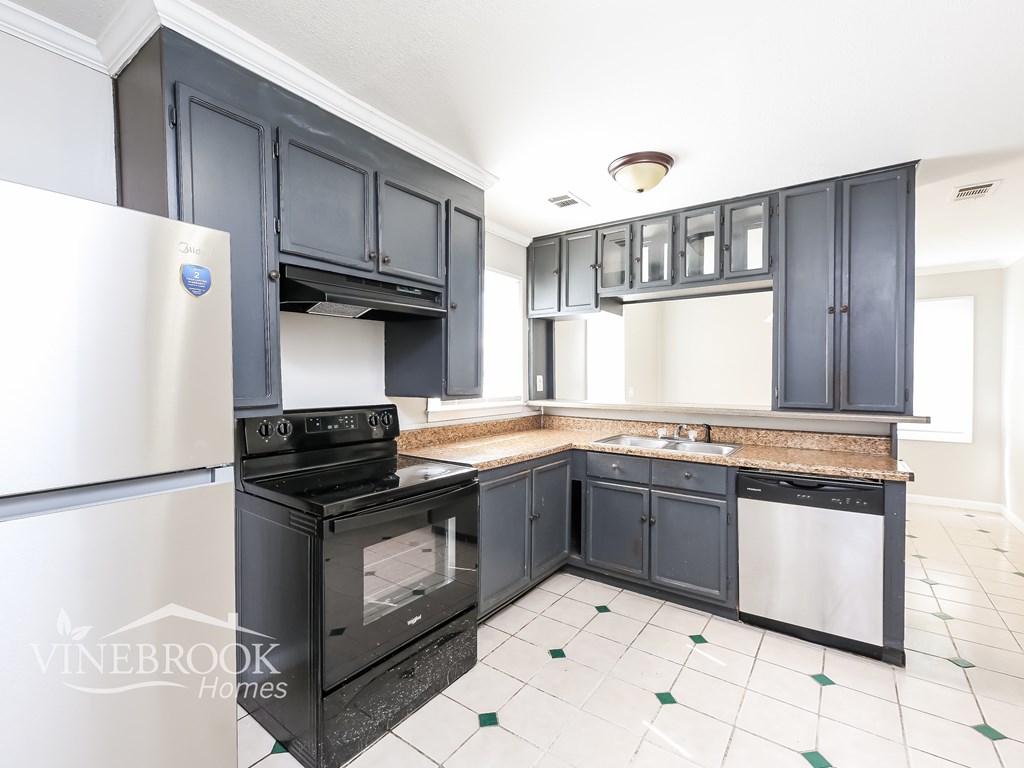 A kitchen with black cabinets and a white fridge.