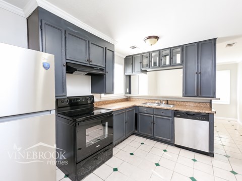 A kitchen with black cabinets and a white fridge.