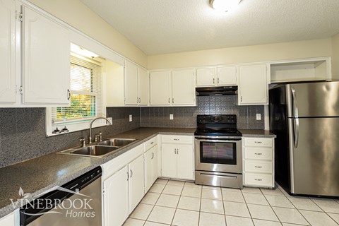 A kitchen with white cabinets and a stainless steel refrigerator.