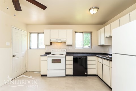 A white kitchen with a black fridge and stove.
