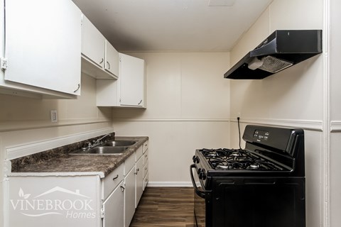 A kitchen with a black stove and white cabinets.