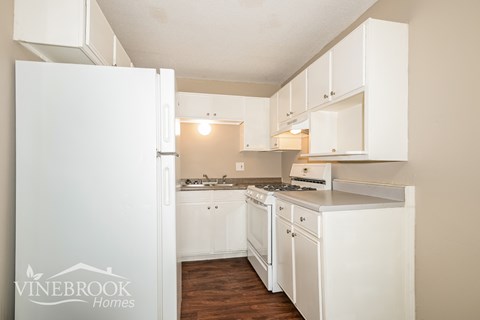 A kitchen with white appliances and cabinets.