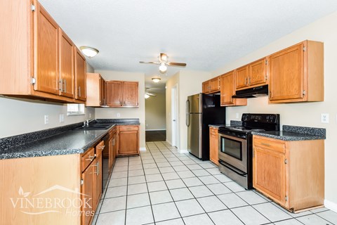 A kitchen with wooden cabinets and black appliances.
