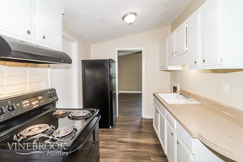 A kitchen with a black stove top oven and white cabinets.