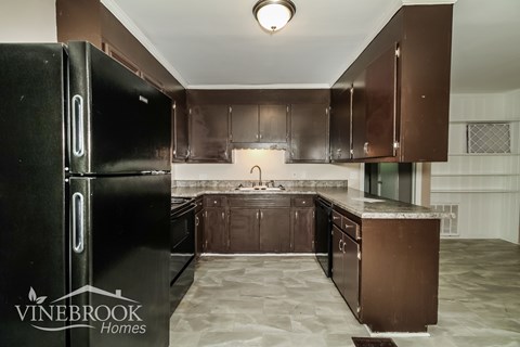 A black fridge in a kitchen with brown cabinets.