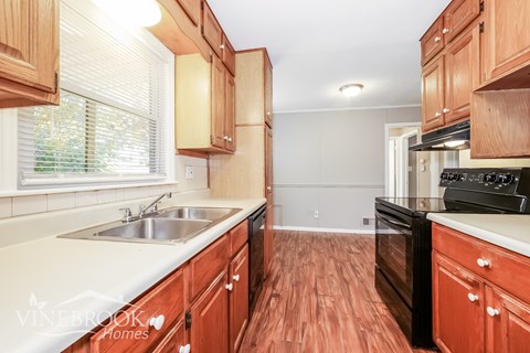 A kitchen with wooden cabinets and a stove top oven.