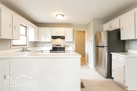 A kitchen with white cabinets and appliances.