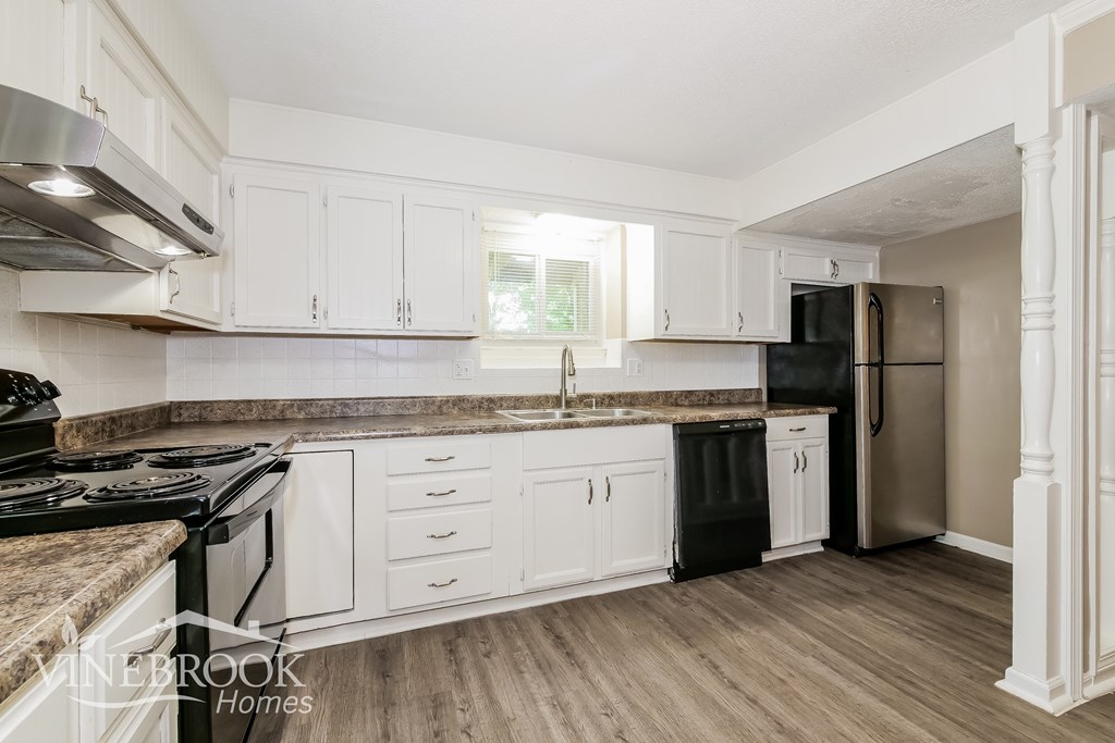 A kitchen with white cabinets and a black stove top.
