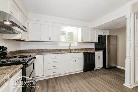 A kitchen with white cabinets and a black stove top.