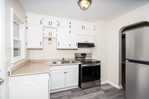 A kitchen with white cabinets and a black fridge.