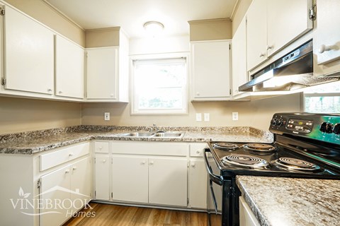 A kitchen with white cabinets and a granite countertop.