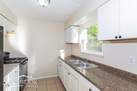 A kitchen with white cabinets and a granite counter top.
