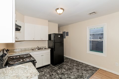 A kitchen with a black refrigerator and a window.
