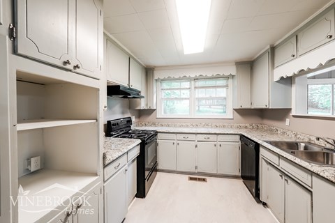 A kitchen with white cabinets and a window.